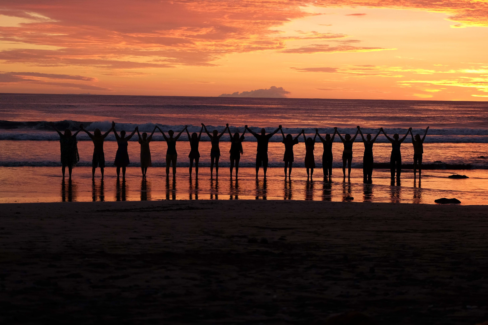 a group of retreat participants on the beach at sunrise