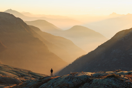 Man looking at the colorful layers of mountains during sunset