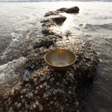Tibetan singing bowl on a strip of reef in the center of the sea. Place for inscription. Photo for advertising. Sound therapy. Healing the body.